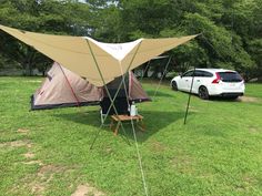 two tents set up in the grass next to a car