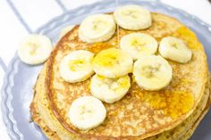 pancakes with banana slices and syrup on a blue plate next to a white towel,