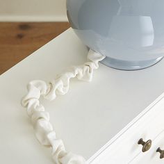 a close up of a white drawer on a table with a blue vase in the background