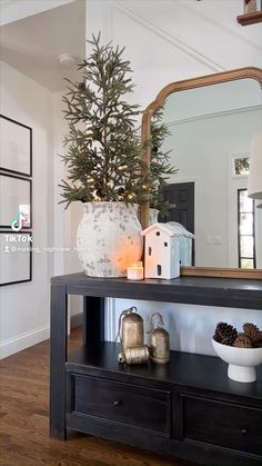 a christmas tree sitting on top of a wooden table next to a mirror and other decorations