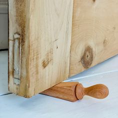 a close up of a wooden door handle on a white painted surface with wood grain