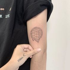 a person with a tattoo on their arm pointing at the air balloon that is flying in the sky