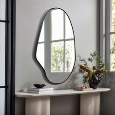 a mirror sitting on top of a white table next to a vase filled with flowers