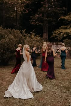 a bride and her bridal party dancing in the woods at their wedding reception,