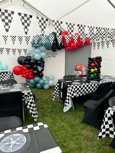 an outdoor party with black and white checkered tablecloths, balloons and decorations