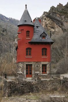 an old red brick building with a black roof and steeple on the mountain side