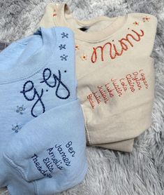 two baby ones laying on top of a white carpet next to each other, one with the word mama written on it