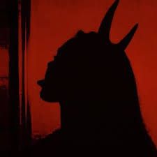 the silhouette of a goat in front of a red sky