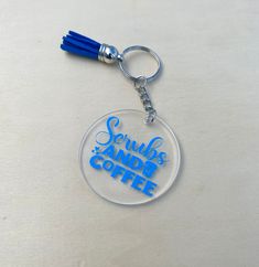 a glass keychain with the words scrubs and coffee printed in blue on it