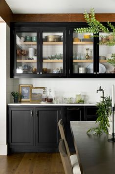 a kitchen with black cabinets and wooden floors