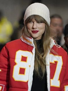 a woman with long hair wearing a red jacket and white hat