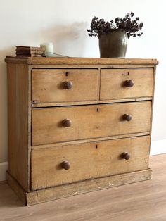 an old wooden dresser with drawers and a potted plant sitting on top of it