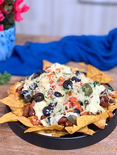 a black bowl filled with nachos on top of a wooden table