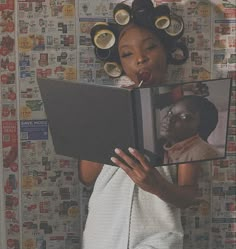 a woman with curlers on her head holding a book in front of her face