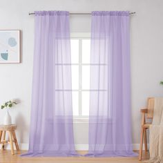 a room with a chair and window covered in purple sheer curtaines on the windowsill