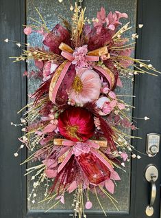 a pink and red wreath hanging on the front door