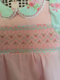 a pink and green dress with roses on the bottom, along with lace trimmings