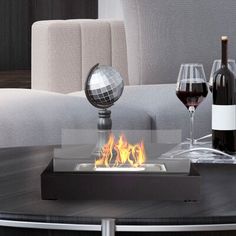 a table that has some wine glasses on top of it and a fire pit in the middle