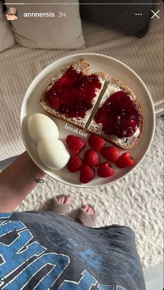 someone is holding a plate with toast and strawberries on it