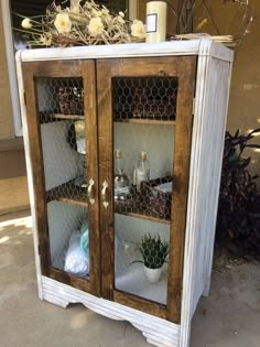 an old cabinet with chicken wire and glass doors is sitting outside on the concrete floor