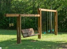 a wooden swing set with swings in the grass