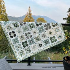 a quilted table runner sitting on top of a wooden deck next to a potted plant