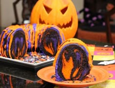 a cake with purple and orange icing sitting on top of a table next to a plate