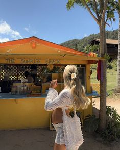 a woman standing in front of a food stand with her hand up to the sky