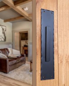 a door handle on a wooden door in a living room with a couch and coffee table