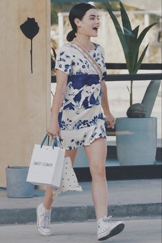 a woman walking down the street with shopping bags in her hand and laughing at someone