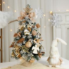 a small christmas tree with gold and silver ornaments on it next to a stuffed animal