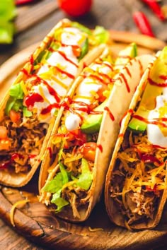 three tacos on a wooden platter with toppings