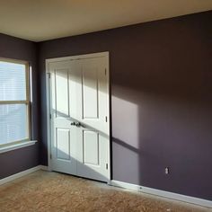 an empty room with purple walls and white doors