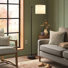 a living room filled with furniture and a lamp on top of a wooden floor next to a window