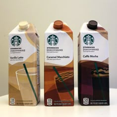 three starbucks drink cartons sitting next to each other