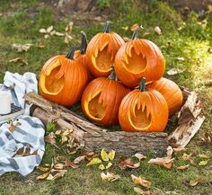 several carved pumpkins sitting in a basket on the grass