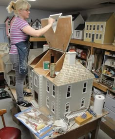 a woman is working on a model house