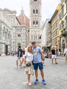 a man and woman are standing in the middle of a street with tall buildings behind them