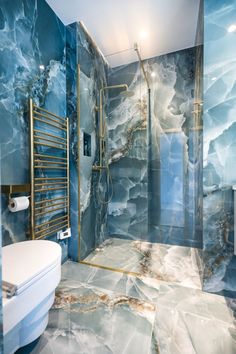 a bathroom with blue marble walls and flooring, gold accents on the shower wall