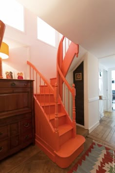 an orange stair case in the entryway of a house