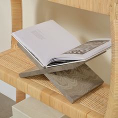 an open book sitting on top of a wooden chair next to a stack of books