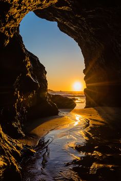 the sun is setting in an ocean cave