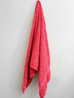 a bright pink towel hanging on the wall next to a white wall with a black hook