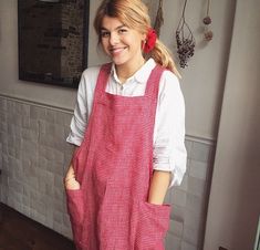 a woman wearing an apron standing in front of a wall with hanging items on it