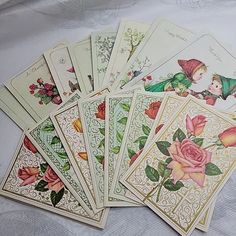 a bunch of cards that are laying on a tablecloth with white sheets and flowers