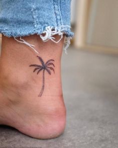 a small palm tree tattoo on the bottom of a person's foot with blue jeans