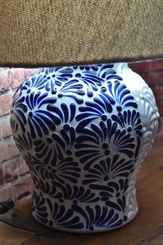 a blue and white vase sitting on top of a wooden table next to a lamp