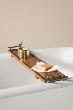 a bathtub with soap and other items on the tray in front of it,