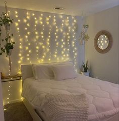 a bed with white sheets and lights on the wall above it, in a bedroom