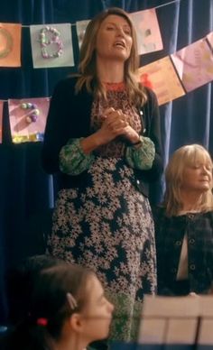 a woman standing in front of a group of children with their hands together and looking up